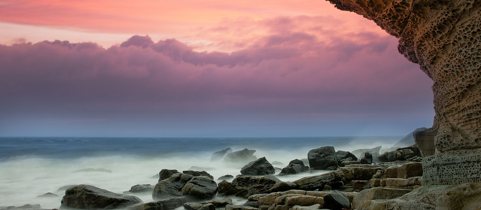 Bild von einem Strand mit Meeresgischt und Felsen